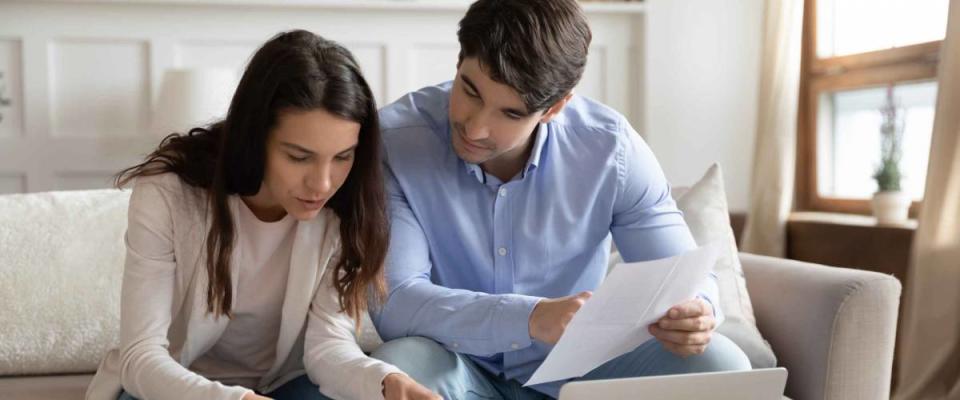 Close up young couple checking mortgage or loan agreement.