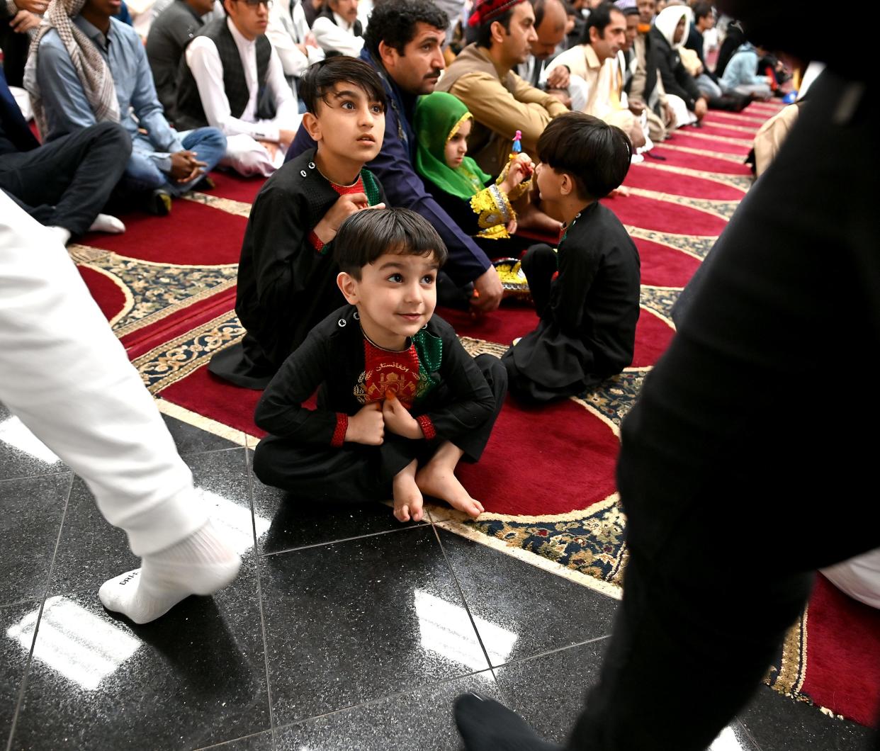 Three-year-old Zahidulla, front, and Favhadulla, 9, both of whom recently emigrated with their families to Worcester from Afghanistan, watch as fellow Muslims enter for a special prayer to start the Eid al-Fitr celebration at the Worcester Islamic Center on Friday.