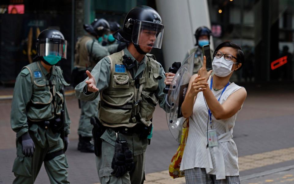 Riot policeman pushes a woman as she is taking a photograph of detained protesters - AP
