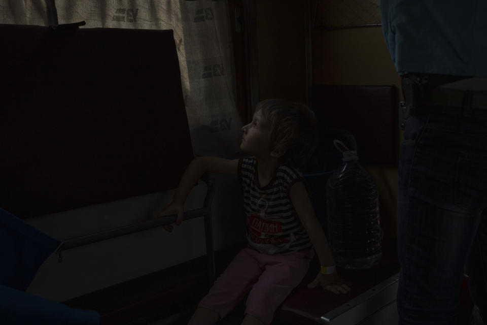 Internally displaced from Sloviansk, 5-year old Hena, looks out the window on a train heading to Dnipro, in the Pokrovsk train station, Donetsk region, eastern Ukraine, Wednesday, July 6, 2022. Many are responding to the authorities' pleas to evacuate. As Russian troops march west, a steady flow of people continue to evacuate from towns caught in the crosshairs of the war, with hundreds leaving on a daily evacuation train from Pokrovsk. (AP Photo/Nariman El-Mofty)