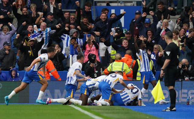 Brighton players pile on in the corner after Joao Pedro's late winner