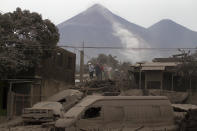 <p>Rescue workers walk on rooftops in Escuintla, Guatemala, June 4, 2018, blanketed with heavy ash spewed by the Volcan de Fuego, or “Volcano of Fire,” pictured in the background, left center. (Photo: Luis Soto/AP) </p>