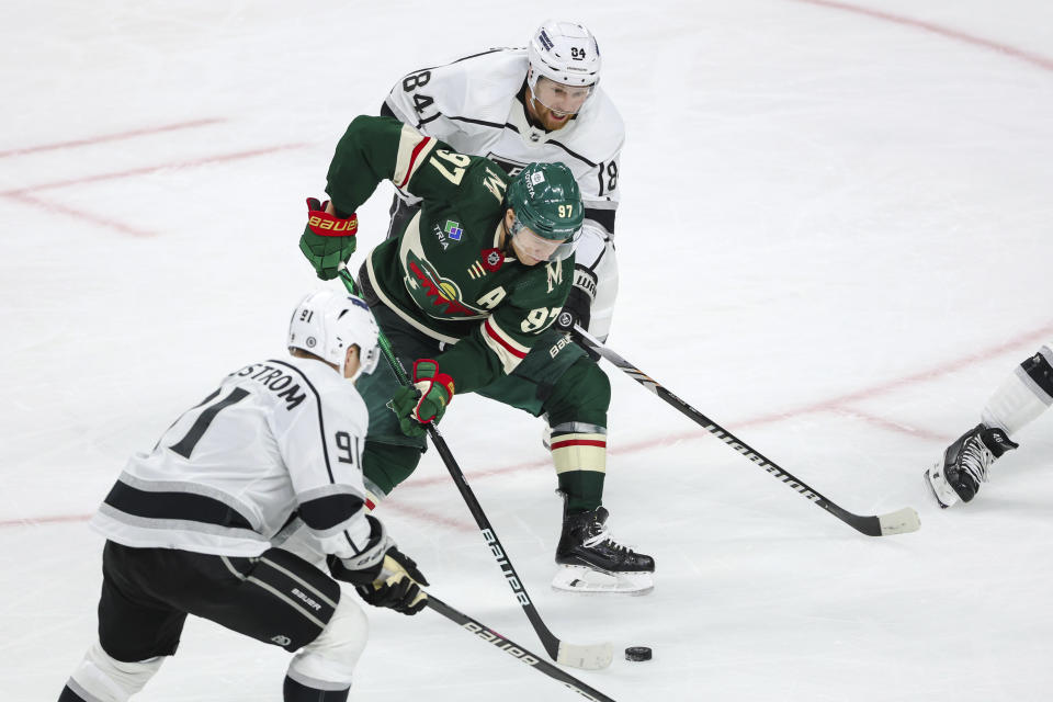 Minnesota Wild left wing Kirill Kaprizov, center, skates with the puck while Los Angeles Kings defenseman Vladislav Gavrikov (84) and right wing Carl Grundstrom (91) defend during the third period of an NHL hockey game Thursday, Oct. 19, 2023, in St. Paul, Minn. (AP Photo/Matt Krohn)