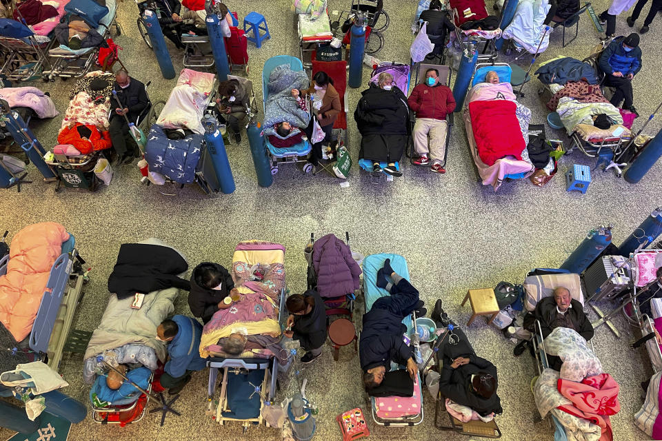 People look after their elderly relatives lying on stretchers and receiving intravenous drips while using ventilators at the Changhai Hospital hall in Shanghai, China, Tuesday, Jan. 3, 2023. As COVID-19 rips through China, other countries and the World Health Organization are calling on its government to share more comprehensive data on the outbreak. Some even say many of the reported numbers are meaningless. (Chinatopix Via AP)