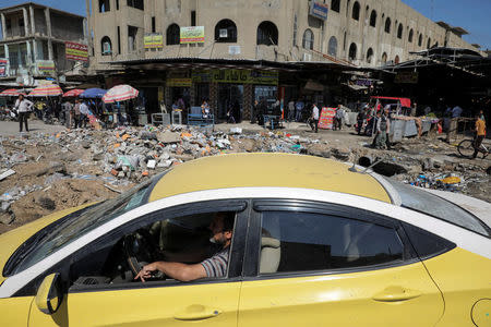 A man drives a car past a market in eastern Mosul, Iraq, April 19, 2017. REUTERS/Marko Djurica