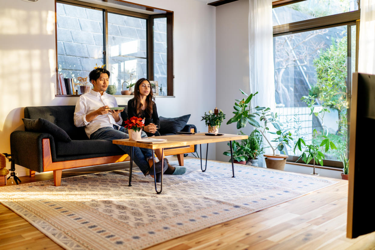 A young couple is spending their time together watching tv at home.