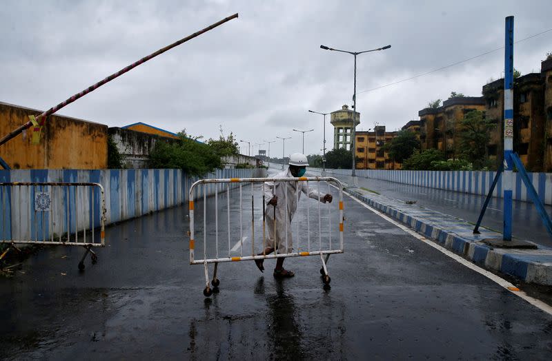 A police officer moves a barricade to block a road before Cyclone Amphan makes its landfall, in Kolkata