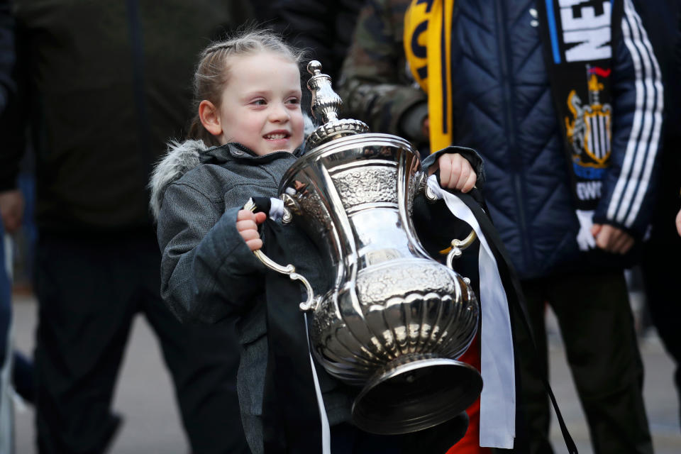 NEWCASTLE UPON TYNE, ENGLAND - JANUARY 25: A young fan lifts a model FA cup prior to the FA Cup Fourth Round match between Newcastle United and Oxford United at St. James Park on January 25, 2020 in Newcastle upon Tyne, England. (Photo by Ian MacNicol/Getty Images)