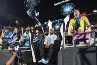 Former Carolina Panthers wide receiver Steve Smith, center, sits near fans before an MLS soccer match between Charlotte FC and the LA Galaxy in Charlotte, N.C., Saturday, March 5, 2022. (AP Photo/Jacob Kupferman)