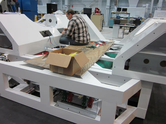 A NASA engineer works on a mockup of the sled component of the SEV spacecraft, attaching wiring onto this preliminary prototype.