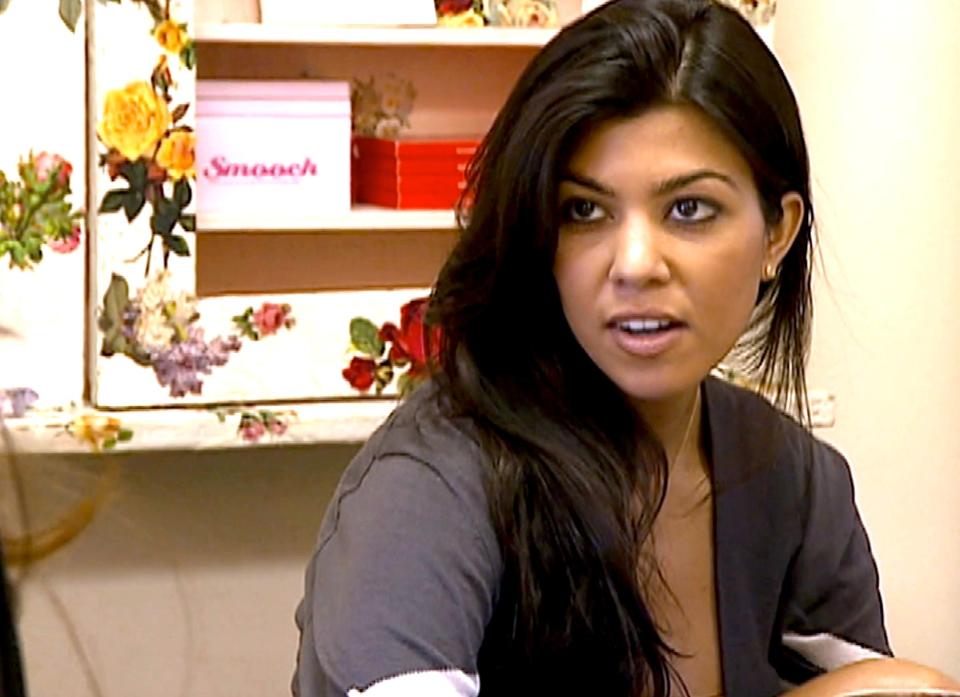 Kourtney Kardashian sitting indoors and engaged in a conversation