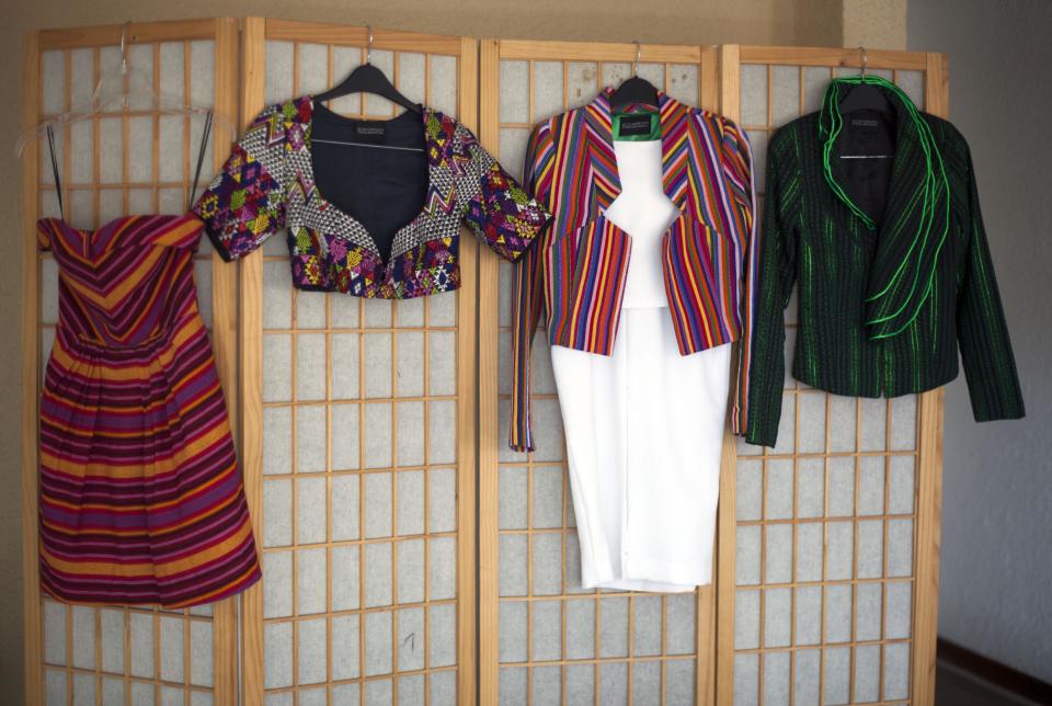 In this Aug. 21, 2013 photos, original designs by Guatemalan designer Eduardo Figueroa, hang on a room divider in his studio in Guatemala City. Figueroa, a high-couture designer, said modernizing the Mayan designs helps non-indigenous people appreciate this "ethnic" fashion. "I am inspired by color and Guatemalan textiles are rich in color," Figueroa said. "There were people who would tell you that they thought that traditional textiles were just for cushions and tablecloths, but I tell them that they can be used in many ways." (AP Photo/Luis Soto)