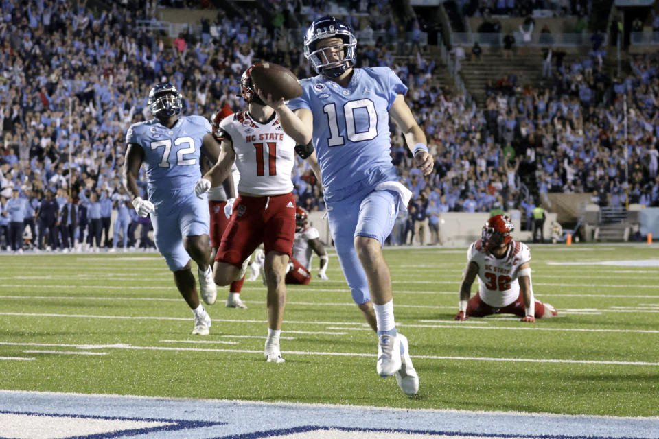 FILE - North Carolina quarterback Drake Maye (10) rolls into the end zone for a touchdown as North Carolina State linebacker Payton Wilson (11) trails during the second half of an NCAA college football game Nov. 25, 2022, in Chapel Hill, N.C. Maye has made a rapid rise to stardom to be a top NFL quarterback prospect and a Heisman Trophy candidate. (AP Photo/Chris Seward, File)