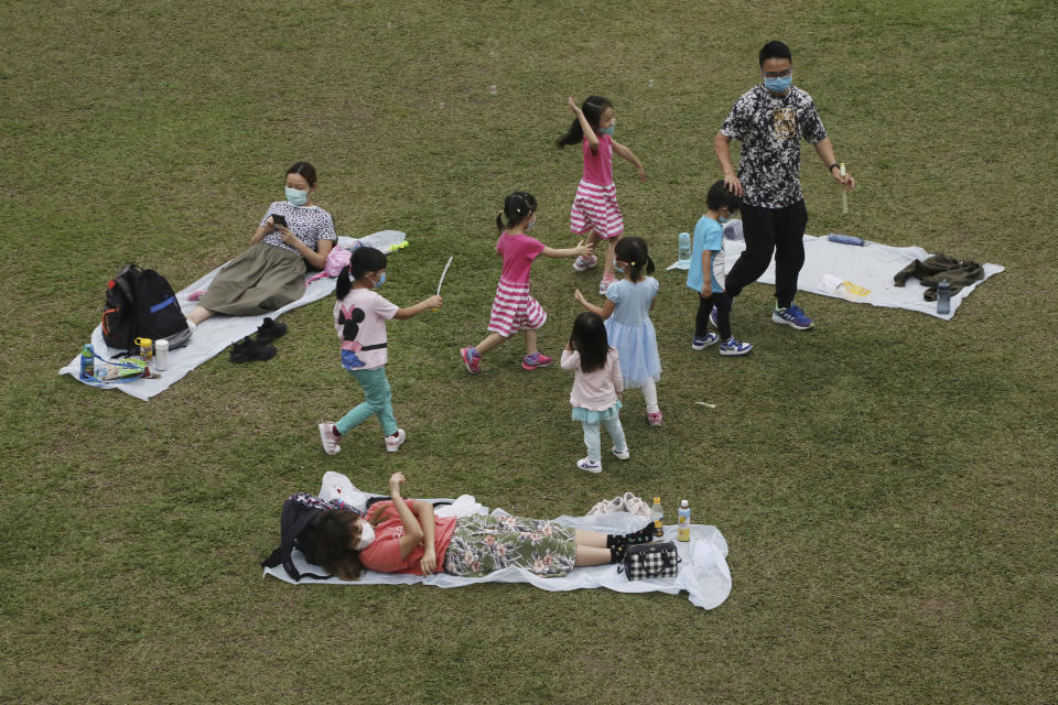 People wearing face masks to protect themselves from possibly contracting the coronavirus COVID-19 enjoy time out at a park in Hong Kong, Saturday, April 18, 2020. (AP Photo/Kin Cheung)