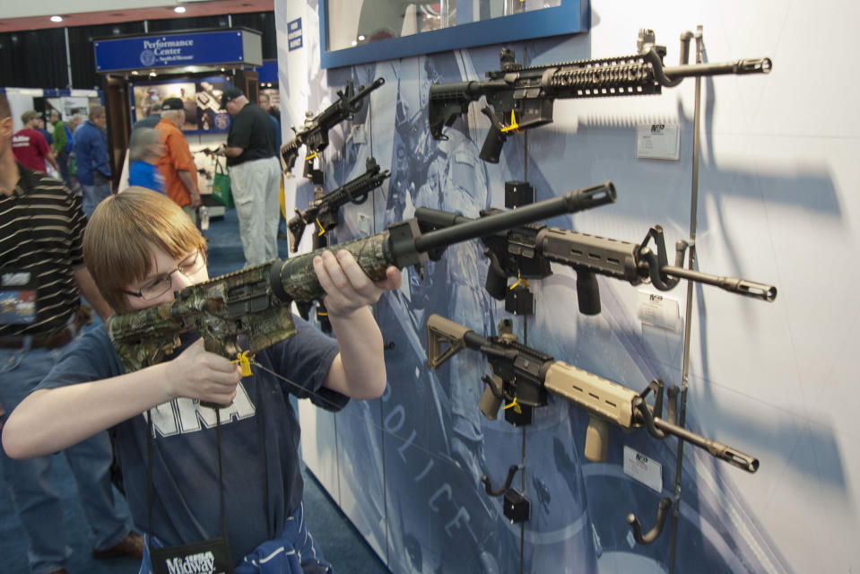 FILE - In this May 3, 2013, file photo, a young man holds an assault style rifle during the National Rifle Association's annual convention in Houston. The National Rifle Association is gathering for its 148th annual meeting beginning Thursday, April 25, 2019, in Indianapolis. (AP Photo/Steve Ueckert, File)