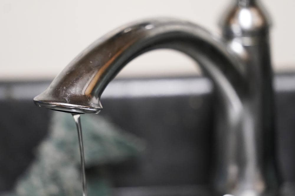 A trickle of water comes out of the faucet of Mary Gaines a resident of the Golden Keys Senior Living apartments in her kitchen in Jackson, Miss., Sept. 1, 2022. (AP Photo/Steve Helber, File)