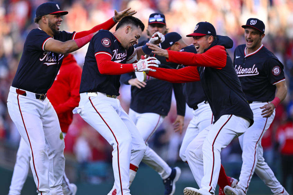 Washington Nationals' Joey Meneses, center left, is mobbed by teammates after driving in the game winning run in the 10th inning of a baseball game against the Houston Astros at Nationals Park, Saturday, April 20, 2024, in Washington. (AP Photo/John McDonnell)