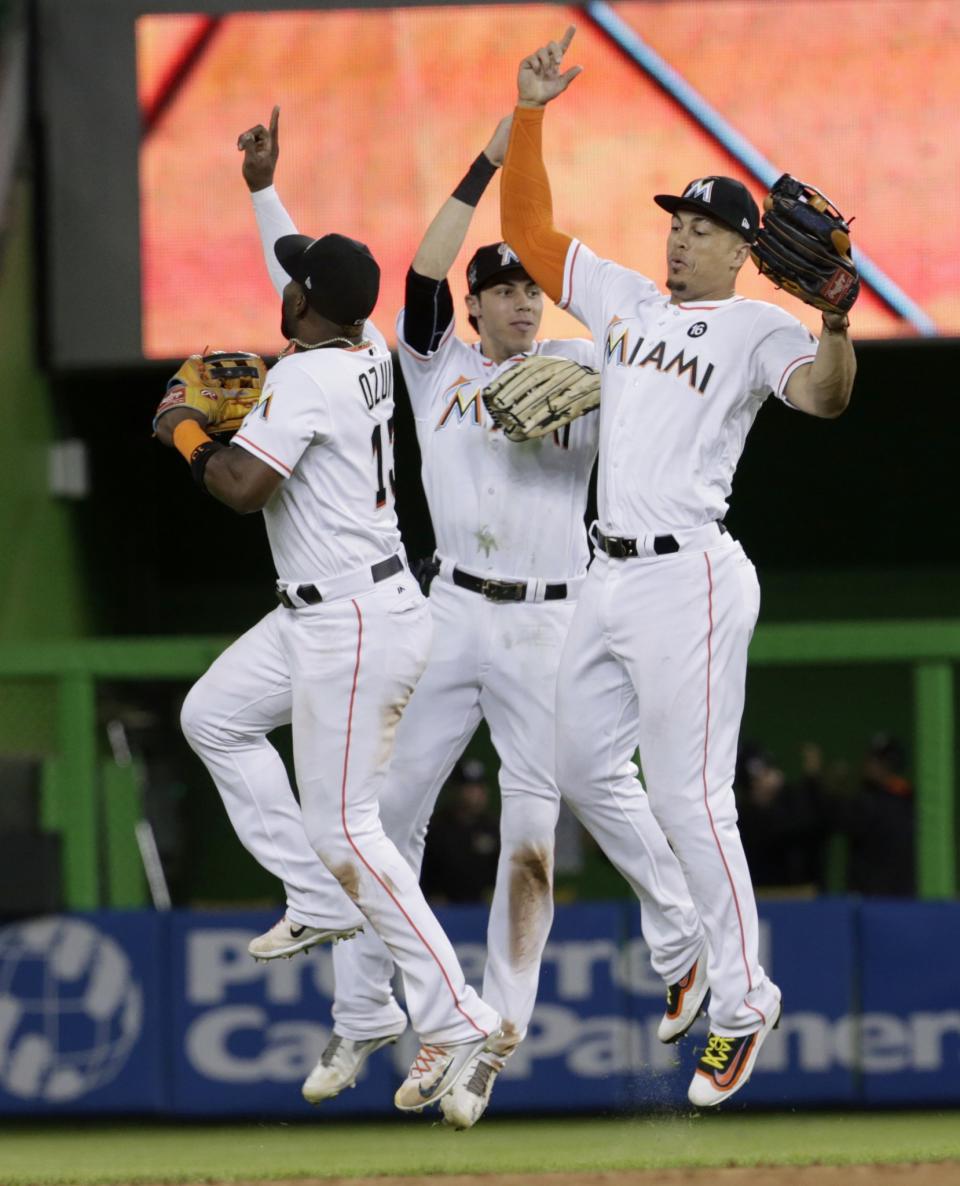 Marcell Ozuna (left) and Christian Yelich (center) celebrate with Giancarlo Stanton following his game-ending and home run-saving catch. (AP)