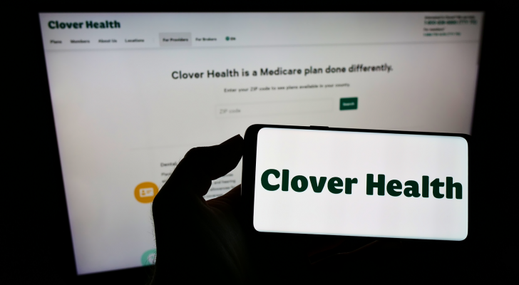 Person holding smartphone with logo of healthcare company Clover Health (CLOV Stock) Investments Corp on screen in front of website