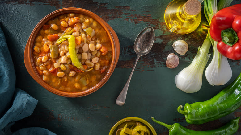 Bowl of baked beans next to spoon and veggies