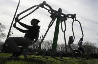 FILE - In this file photo dated Saturday, March 21, 2020, people use outdoor public gym equipment at a park after indoor gyms were asked to close by the government to help limit the spread of coronavirus in London. The British government insists that science is guiding its decisions as the country navigates its way through the coronavirus pandemic. But a self-appointed group of independent experts led by a former government chief adviser says it sees little evidence-based about Britain’s response. Unlike other countries, the scientific opposition to Britain’s approach is remarkably organized. The independent group sits almost in parallel to the government’s own scientists, assesses the same outbreak indicators and has put out detailed reports on issues such contact tracing, reopening schools and pubs, and relaxing social distancing (AP Photo/Kirsty Wigglesworth, FILE)