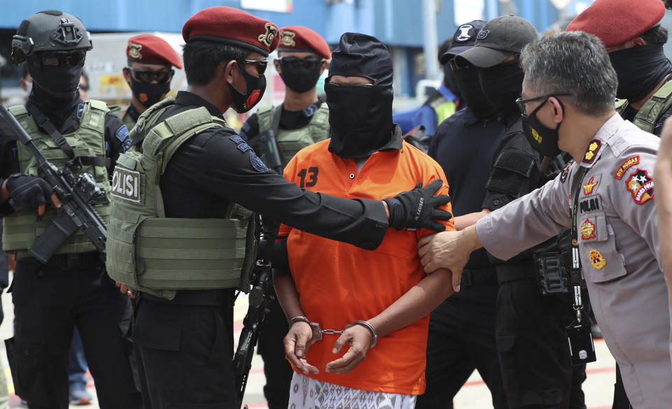 Police officers escort suspected militant Zulkarnaen, center, who is also known as Aris Sumarsono, upon arrival at Soekarno-Hatta International Airport in Tangerang, Indonesia, Wednesday, Dec. 16, 2020. Indonesian authorities have transferred suspected militants arrested in recent weeks to the country’s capital, including Zulkarnaen, a bomb maker and the architect of a series of deadly attacks and sectarian conflicts in the world’s largest Muslim majority nation. (AP Photo/Achmad Ibrahim)