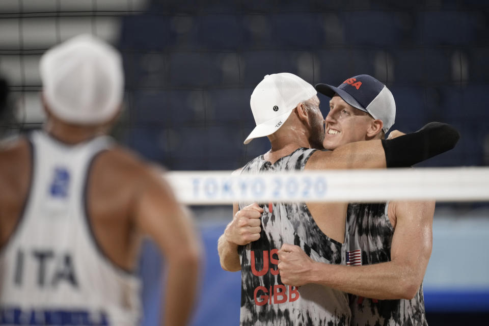 Jacob Gibb, center, of the United States, hugs teammate Tri Bourne after winning a men's beach volleyball match against Italy at the 2020 Summer Olympics, Sunday, July 25, 2021, in Tokyo, Japan. (AP Photo/Felipe Dana)