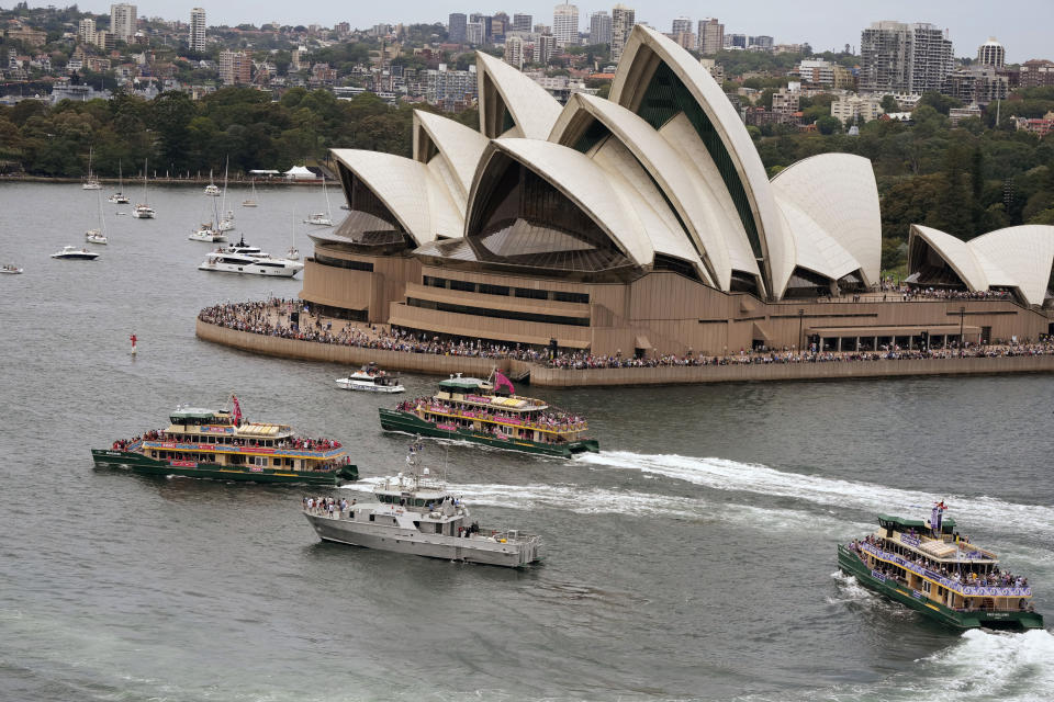 Ferries race between the Opera House and a small navy ship during Australia Day celebrations in Sydney, Friday, Jan. 26, 2024. (AP Photo/Rick Rycroft)