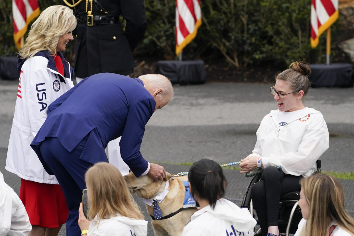 President Joe Biden and first lady Jill Biden stop to pet a service dog as they arrive for an event with the Tokyo 2020 Summer Olympic and Paralympic Games, and Beijing 2022 Winter Olympic and Paralympic Games, on the South Lawn of the White House, Wednesday, May 4, 2022, in Washington. (AP Photo/Evan Vucci)