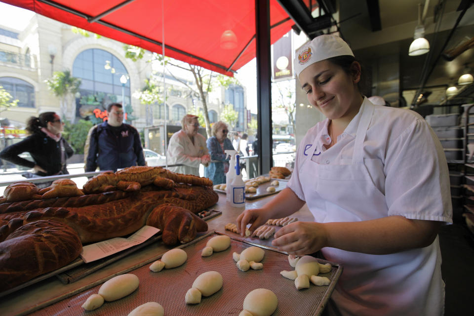 In this photo taken Thursday, May 24, 2012, baker Sarah Haghighi makes turtle-shaped sourdough bread as passerby watch through a window at the Boudin Bakery on Fisherman's Wharf in San Francisco. People can watch the bread being made 24 hours a day and also talk with the bakers through a speaker. (AP Photo/Eric Risberg)