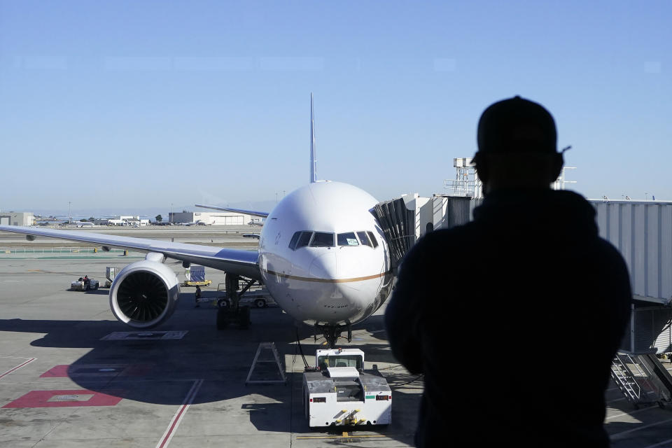 A man looks out of a window toward a United Airlines flight destined for Hawaii at San Francisco International Airport in San Francisco, Thursday, Oct. 15, 2020. Coronavirus weary residents and struggling business owners in Hawaii will be watching closely as tourists begin to return to the islands on Thursday without having to self-quarantine upon arrival. (AP Photo/Jeff Chiu)