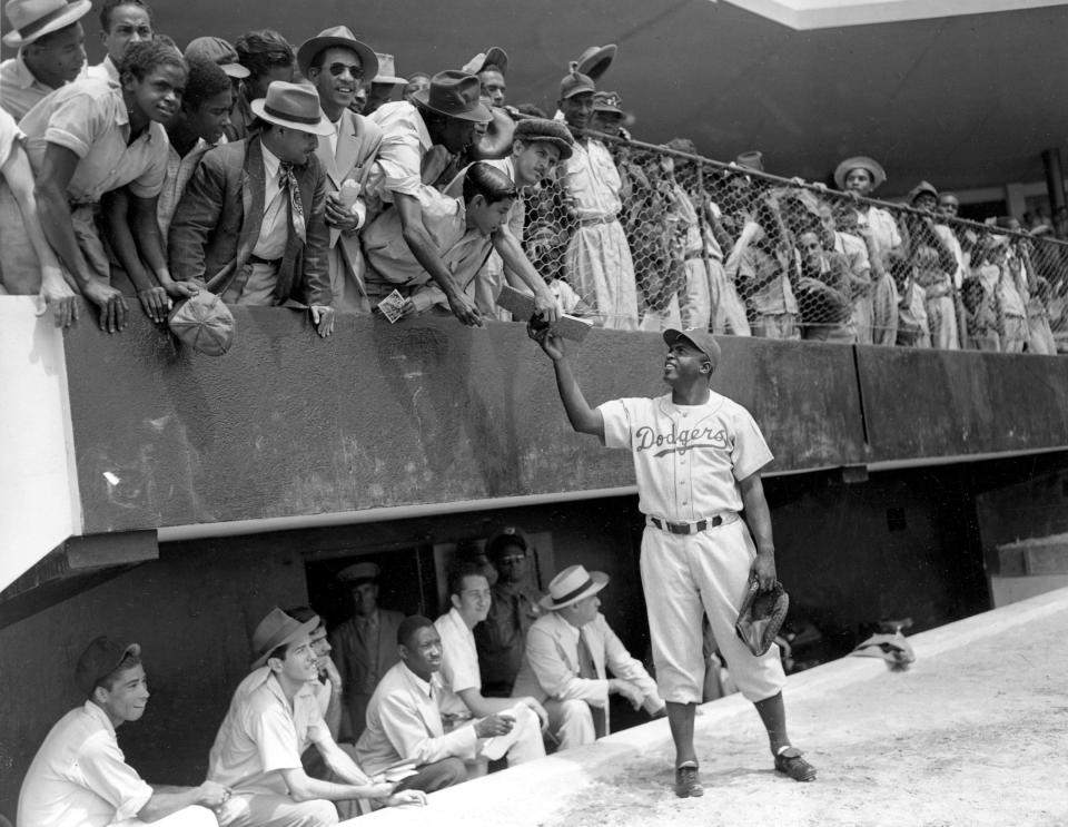 A March 6, 1948, file photo, shows Brooklyn Dodgers first baseman Jackie Robinson returning an autograph book to a fan in the stands, during the Dodgers' spring training in the Dominican Republic.