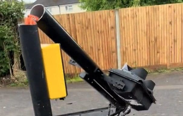 A pole holding traffic lights and a Ulez camera is sawn in half