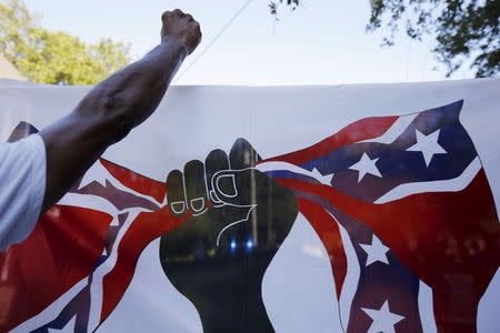 Demonstrators take part in the "March for Black Lives" in Charleston, South Carolina, June 20, 2015, three days after a mass shooting left nine people dead during a bible study at the church. The flag demonstrators carried shows a black fist closing around the confederate flag. REUTERS/Brian Snyder