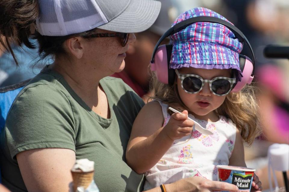 Erica O’Connor of Rocklin holds her daughter Emery, 2, while eating frozen lemonade at the California Capital Airshow on Sunday, Sept. 24, 2023, at Mather Airport.