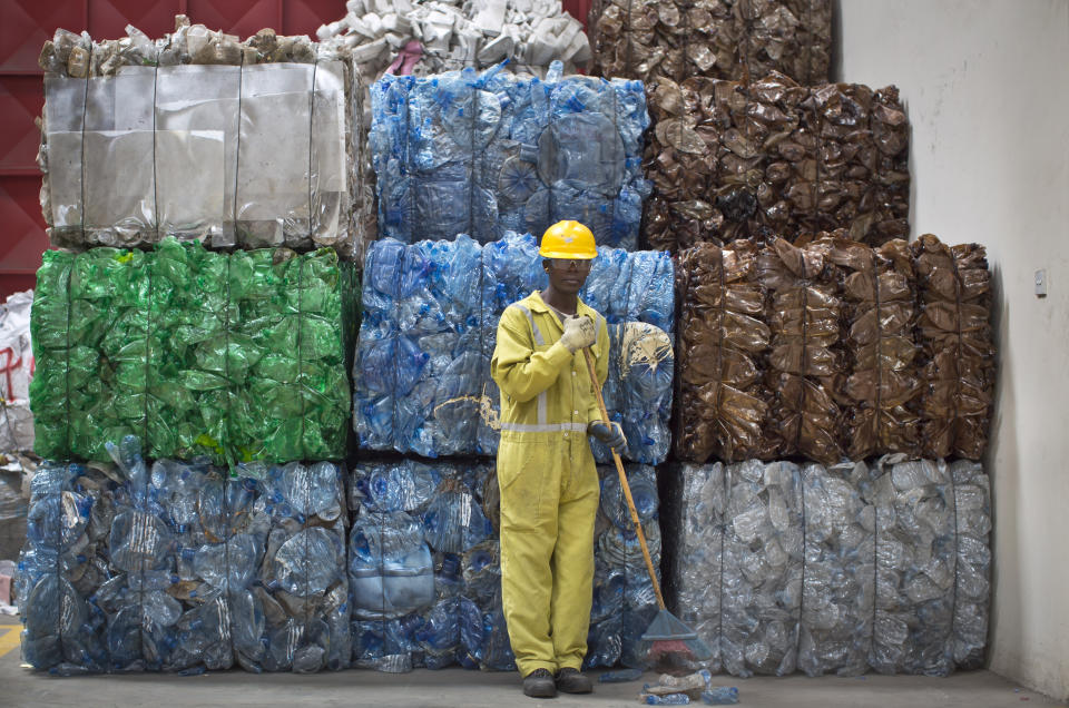 FILE - In this Monday, Aug. 18, 2014 file photo, a worker sweeps the floor next to bundles of flattened plastic bottles ready to be recycled, at the East African Compliant Recycling facility in Machakos, near Nairobi, in Kenya. The oil industry in 2020 has asked the United States to pressure Kenya to change its world-leading stance against the plastic waste that litters Africa, according to environmentalists who fear the continent will be used as a dumping ground. (AP Photo/Ben Curtis, File)