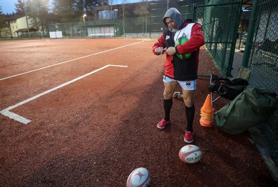 Kitsap Rugby Club Renegades coach Oliver (Ollie) Otterbeck uses a hand pump to fill rugby balls as practice gets under way on the softball field at Naval Base Kitsap-Bangor on March 7.