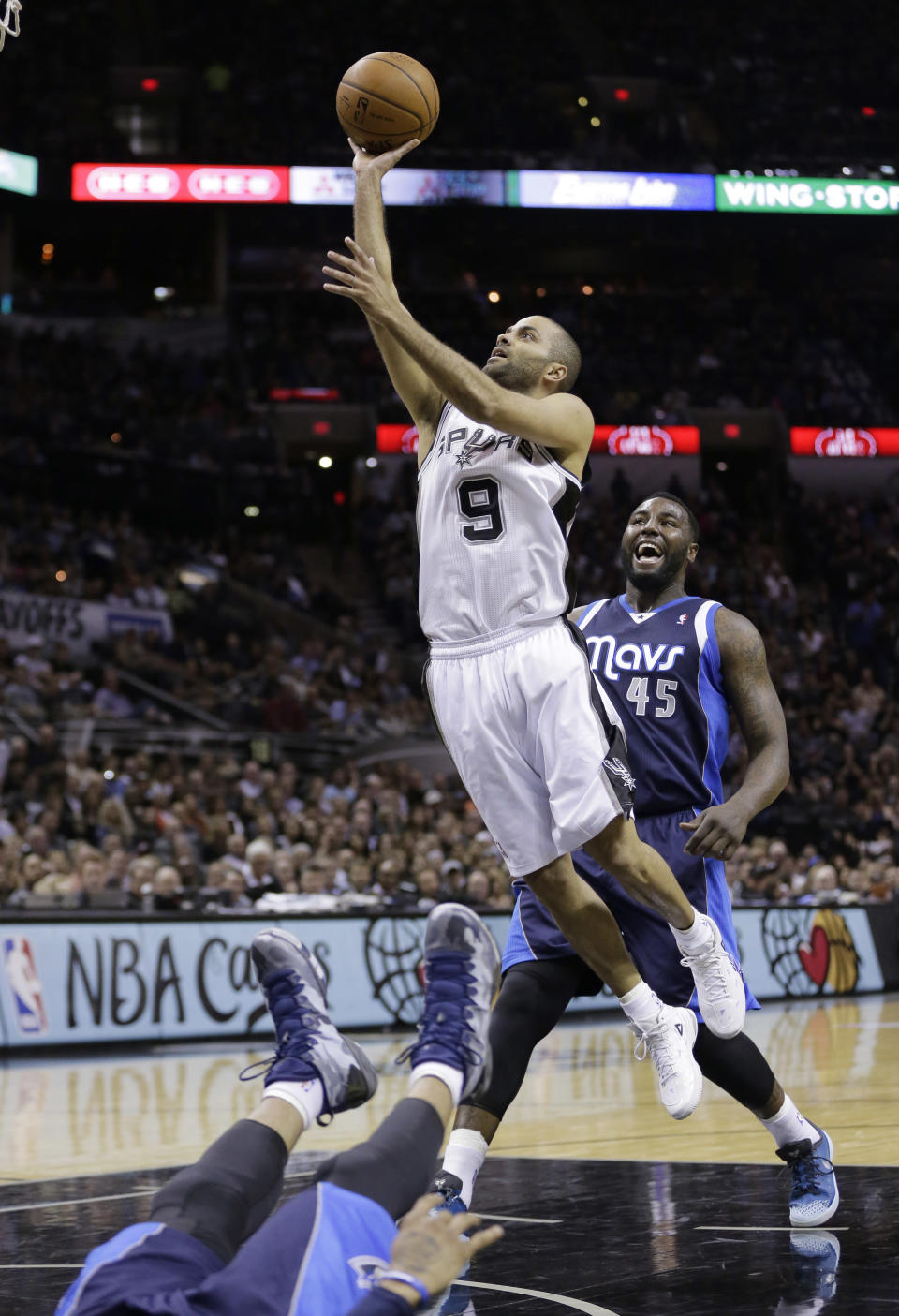 San Antonio Spurs' Tony Parker (9), of France, shoots over a falling Dallas Mavericks' Monta Ellis, left, as Mavericks' DeJuan Blair (45) looks on during the first half of Game 2 of the opening-round NBA basketball playoff series, Wednesday, April 23, 2014, in San Antonio. Parker was called for charging on the play. (AP Photo/Eric Gay)