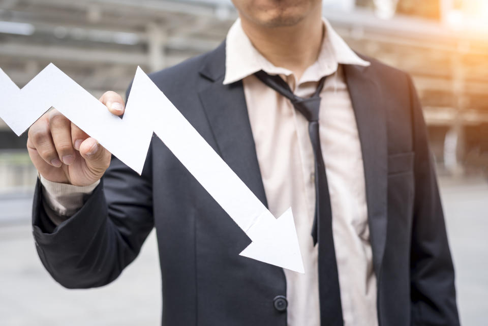 Tired guy in a suit holding a downward sloping arrow.