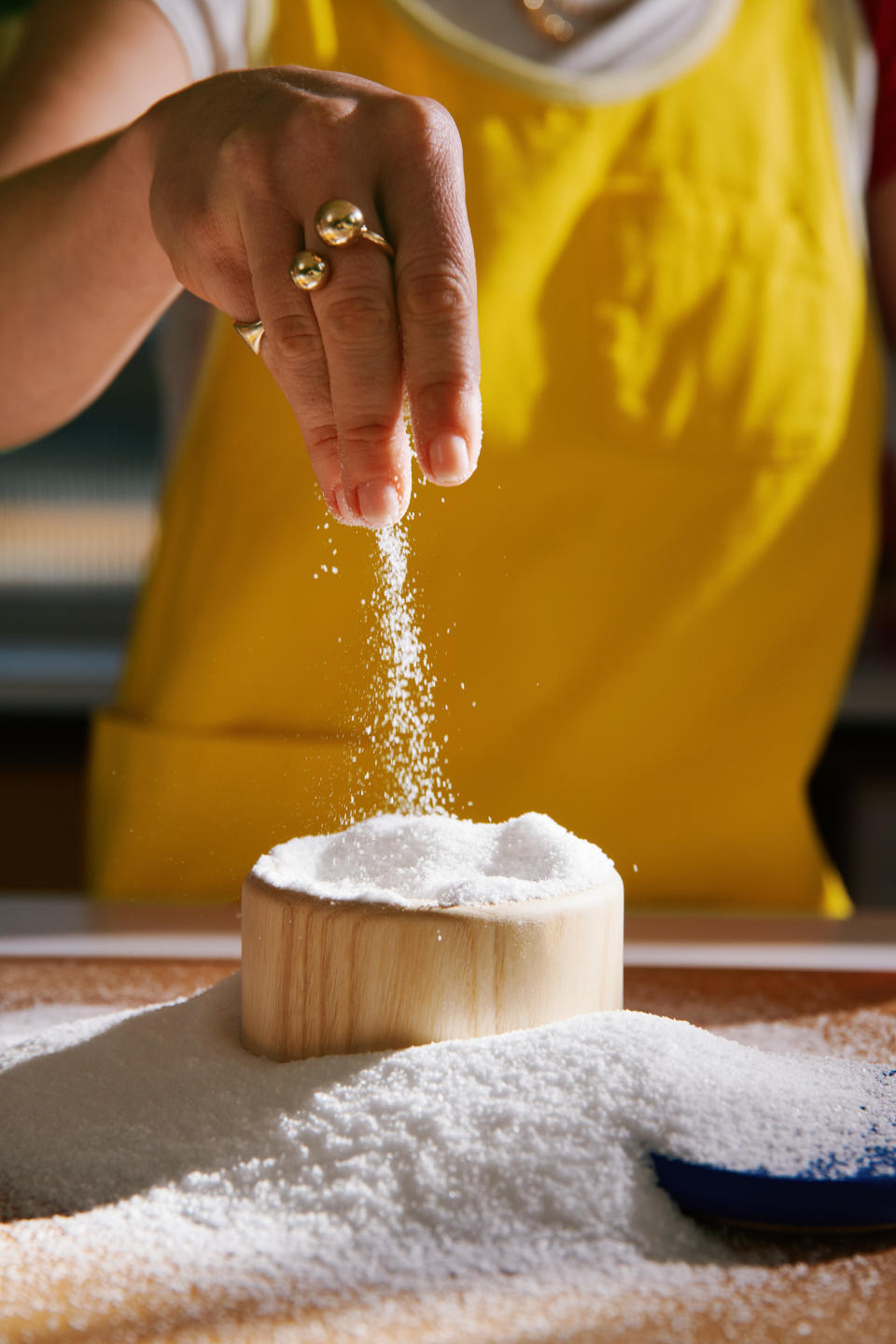 Molly Baz for Crate & Barrel close-up of yellow apron and hand with flour