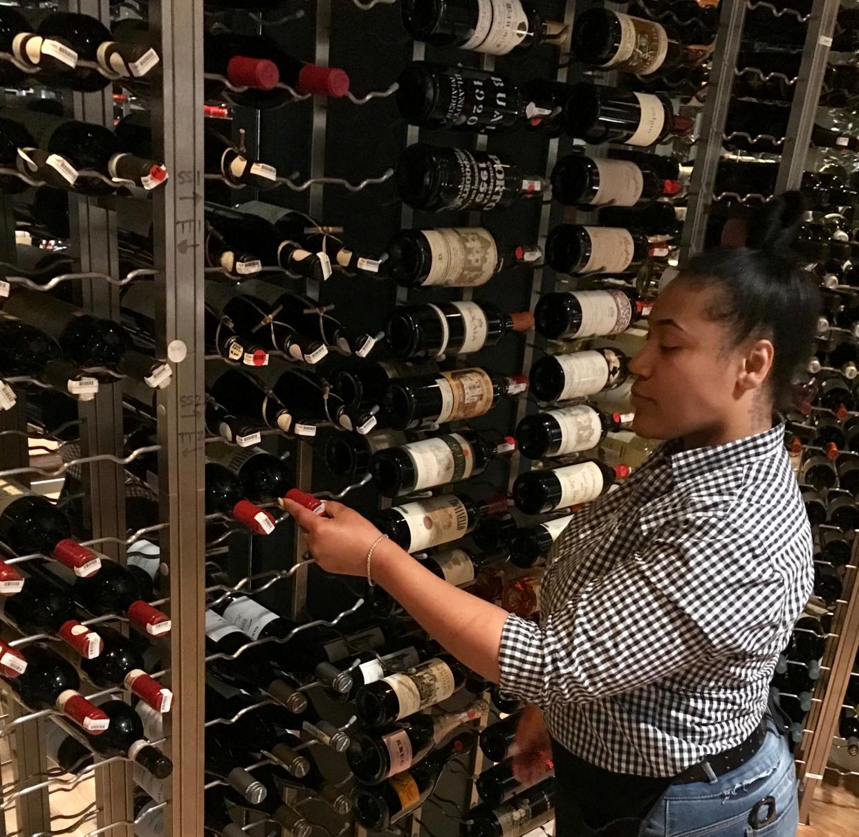 Amber Woods of Clinton, an employee at CAET in Ridgeland, pulls a bottle of wine from the restaurant's wine room.