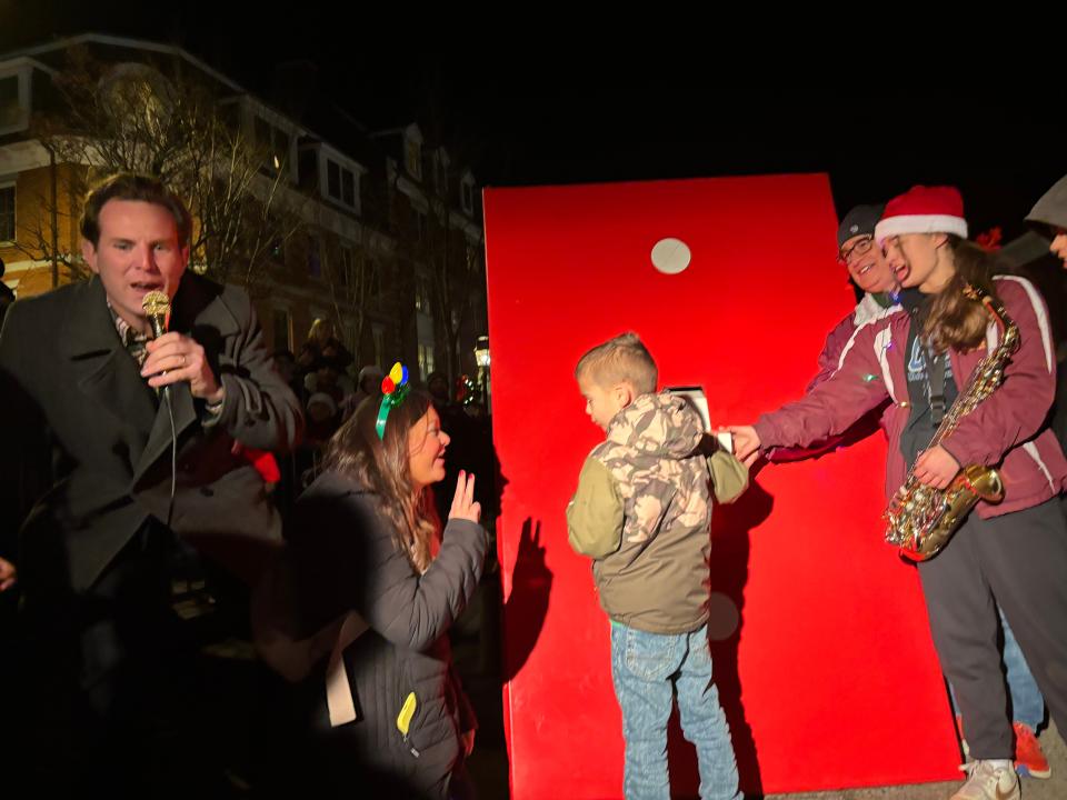 Seven-year-old Cody Bureau is cheered on by the crowd in downtown Portsmouth on Saturday, Dec. 2, 2023 as he flips the switch to turn on the city's holiday tree lights. Bureau was joined by his mother, Christine Bureau and Mayor Deaglan McEachern, far left.