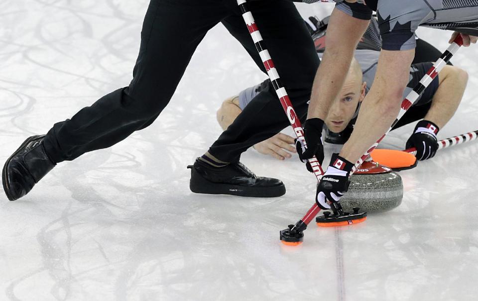Canada's Ryan Fry, center, delivers the rock while teammates Ryan Harnden, left, and E.J. Harnden, right, sweep the ice during the men's curling gold medal game against Britain at the 2014 Winter Olympics, Friday, Feb. 21, 2014, in Sochi, Russia. (AP Photo/Wong Maye-E)