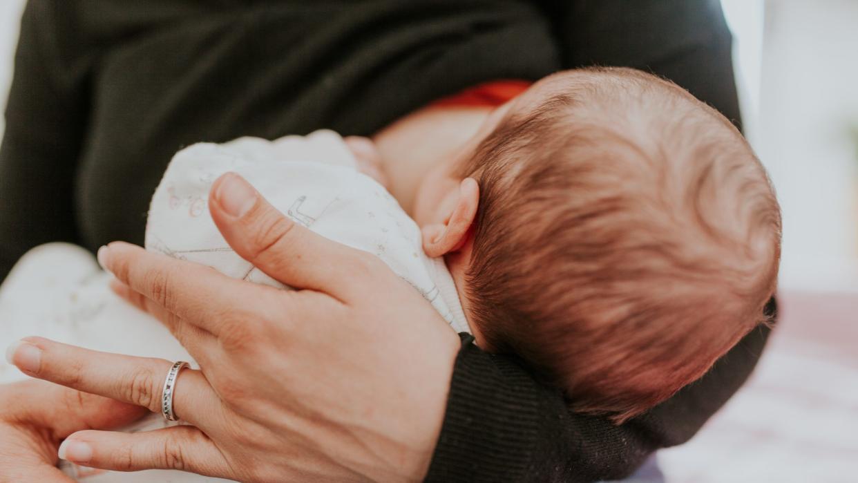 woman breastfeeding baby while suffering from mastitis