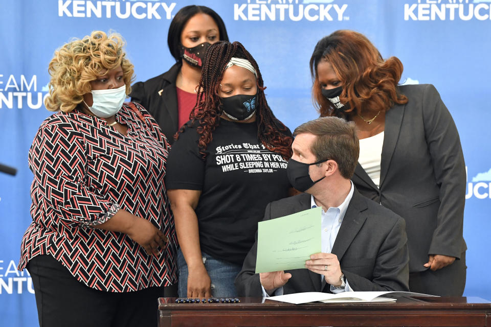 Kentucky Governor Andy Beshear talks with Tamika Palmer, the mother of Breonna Taylor, back row center, following the signing of a partial ban on no-knock warrants at the Center for African American Heritage Louisville, Ky., Friday, April 9, 2021. The bill signing comes after months of demonstrations set off by the fatal shooting of Taylor in her home during a botched police raid. (AP Photo/Timothy D. Easley)
