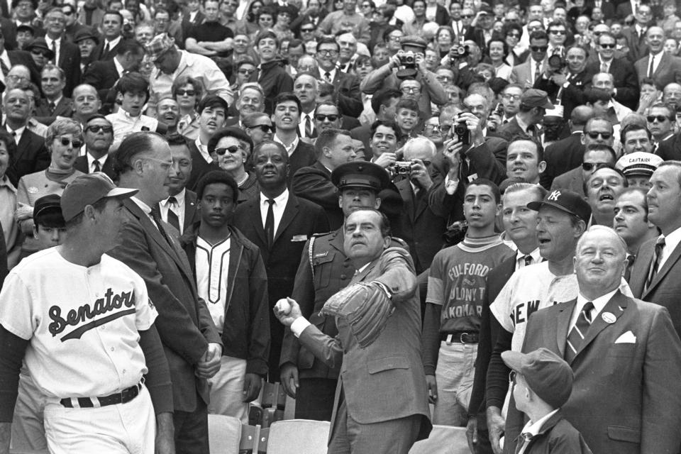 FILE - In this April 7, 1969, file photo, President Richard M. Nixon throws out the ceremonial first pitch in Washington as Baseball Commissioner Bowie Kuhn, second from left, and Washington Senators manager Ted Williams, far left, and others, look on. Growing up in the Washington suburbs during the 1960s, the local baseball team was a lost cause, except for a winning record for the expansion Senators after Ted Williams was lured out of retirement to manage the team. (AP Photo, File)