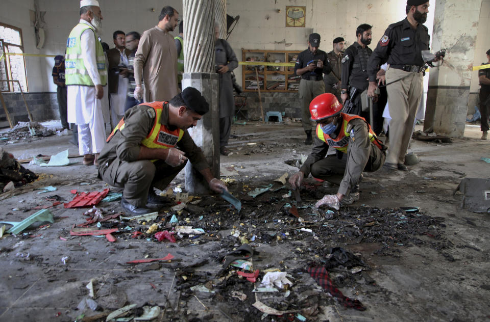 Rescue workers and police officers examine the site of bomb explosion in an Islamic seminary in Peshawar, Pakistan, Tuesday, Oct. 27, 2020. A powerful bomb blast ripped through an Islamic seminary on the outskirts of the northwest Pakistani city of Peshawar on Tuesday morning, killing some students and wounding dozens others, police and a hospital spokesman said. (AP Photo/Muhammad Sajjad)