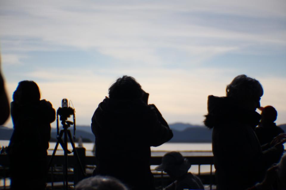 Silhouetted eclipse watchers stand in front of the Lake Champlain