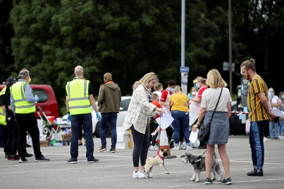 People queue near the Crown and Anchor pub following a spike in cases of the coronavirus disease (REUTERS)