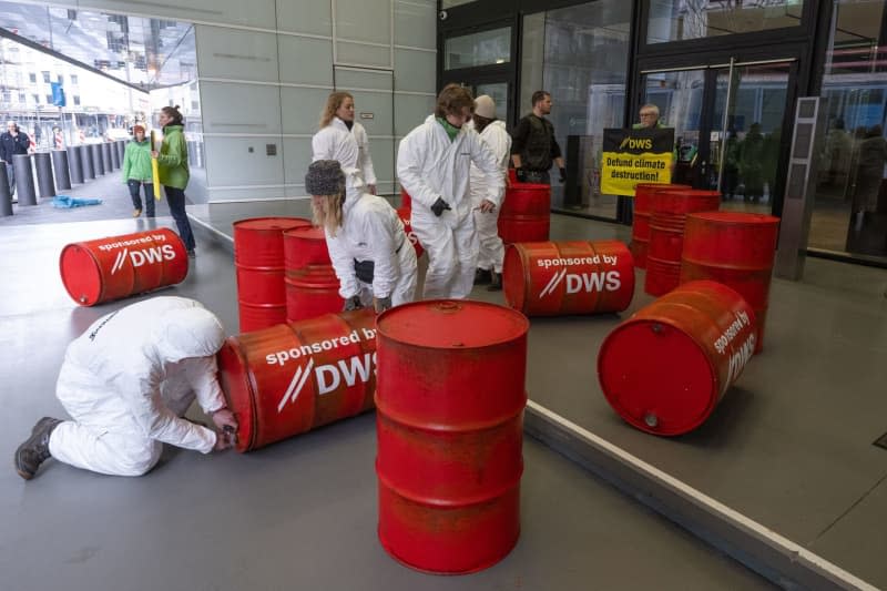 Greenpeace activists protest against investment policy of the DWS Investment's with red oil drums in front of the company's headquarters in Frankfurt. Boris Roessler/dpa